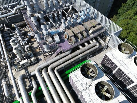 Top down aerial view of complex ventilation ducts and exhaust pipes on industrial rooftop.