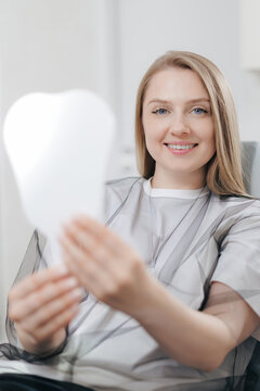 Caucasian female with blonde hair smiling at mirror in dental clinic