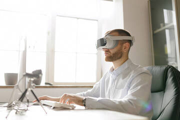 Caucasian male worker adult using vr headset at desk in bright office, immersive technology for work of project