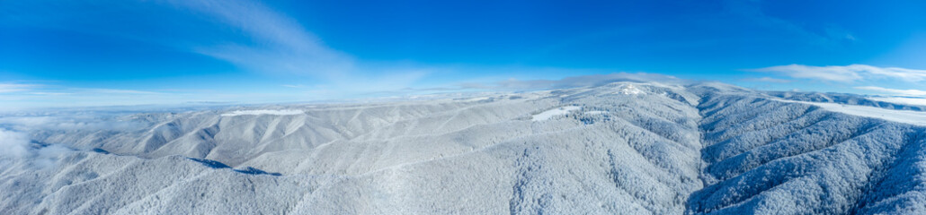 An aerial panoramic view of a snow-covered mountain landscape in winter
