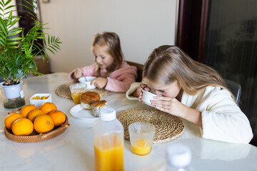 Young girls having breakfast together at home kitchen table