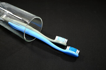 A set of colorful toothbrushes in a clear glass on black background closeup shot, conveying a sense of oral hygiene and daily routine with a touch of vibrancy.