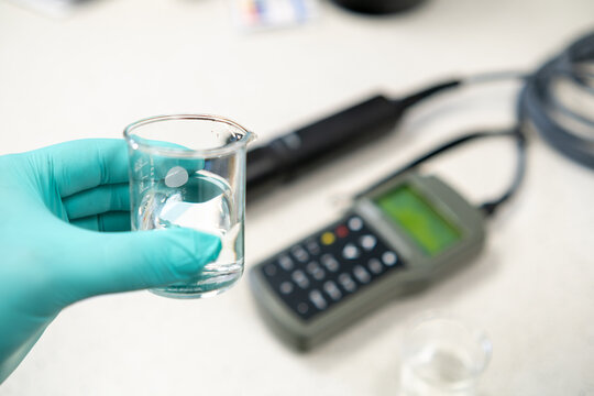 Woman hand in gloves adjusting a pH meter for water analysis