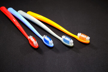 Group of vibrant color toothbrushes layered on a black background, conveying a sense of cleanliness and oral hygiene and daily routine with a touch of vibrancy.