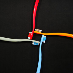 Colorful toothbrushes in red, orange, blue, and grey arranged on black background closeup view, Daily routine concept photography
