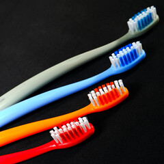 Colorful toothbrushes layered on black background closeup view, Morning routine concept photography selective focused.