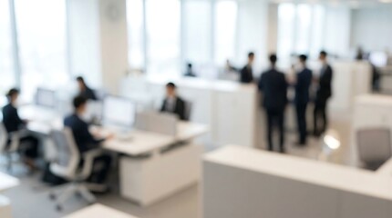 Blurred figures of professionals move and work within a bright, spacious, and modern open-plan office environment, conveying a bustling and active corporate workspace.