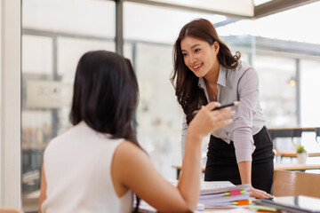 Obraz premium Two busy business professionals women and woman business leaders partners checking document reading financial report talking working together on laptop computer in office at corporate meeting. 