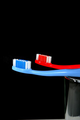A set of colorful toothbrushes on clear glass on black background closeup shot, conveying a sense of oral hygiene and daily routine with a touch of vibrancy. Selective focused 