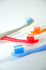 Vibrant toothbrushes in red, orange, blue, and grey arranged on white background, evoking a sense of cleanliness and oral health, Daily routine concept photography