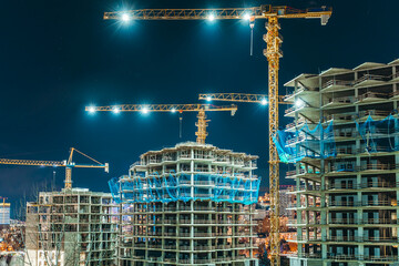 Construction Site at Night with Illuminated Tower Cranes and Building Skeletons
