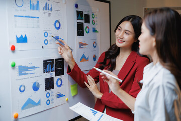 Business professionals discussing market growth and financial results, working together to review statistical information, presenting project strategy and brainstorming ideas on a whiteboard