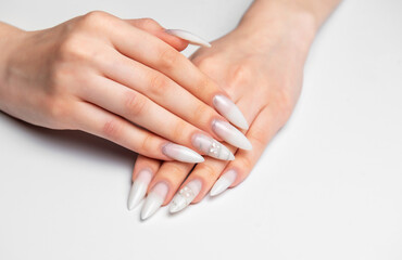 Woman hands showing stiletto nail art manicure wearing white glitter