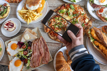 Person taking mobile phone picture of brunch spread