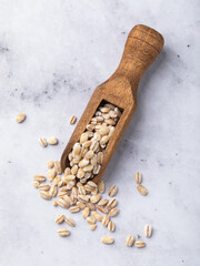 Pearl barley in a wooden scoop on a table, top view, authentic photograph, not AI-generated