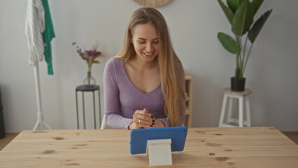 Woman engaged in a video call on a tablet in a cozy living room with natural decor and bright interior, showcasing modern technology use at home.
