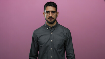 Obraz premium Man standing confidently against a vibrant pink background wearing glasses and a buttoned shirt, exuding a calm and poised demeanor with a modern style.