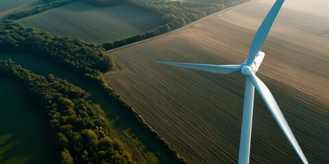 An eye-level view of wind turbine generating renewable energy. Blades spin against the backdrop of fields and trees