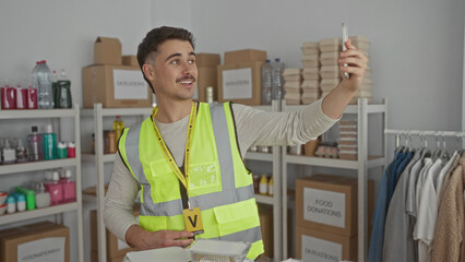 Young hispanic man wearing reflective vest in charity donations center taking a video call...