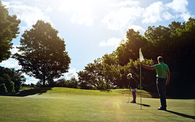 Couple, play and aim with flagstick on golf course for game, practice session and green fairway. People, equipment or target shot for match, golfer technique and recreational sports in countryside