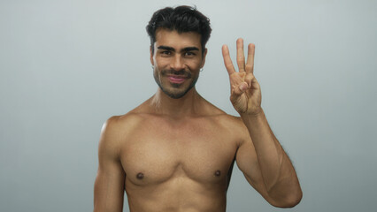 Fototapeta premium Hispanic man with muscular bare chest counting with fingers in lightblue studio on camera; confidence.