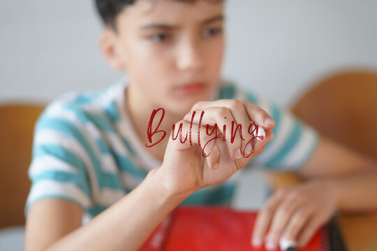 BULLYING. Childhood, preadolescence and adolescence. Pre-adolescent child writing text on the screen with a red marker.
