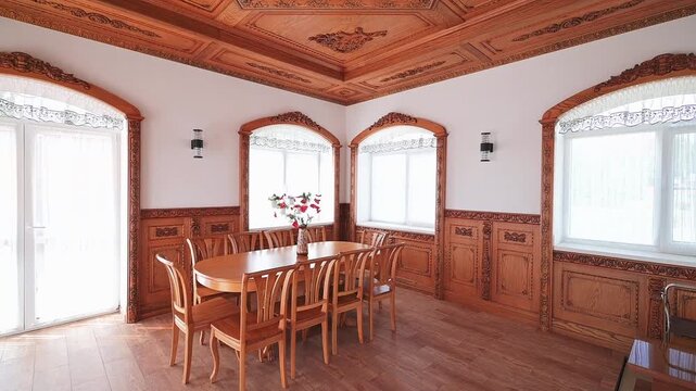 traditional dining room with ornate wooden paneling, arched window frames, a wooden dining set, wall sconces, and a floral centerpiece on the table. Light, airy ambiance.
