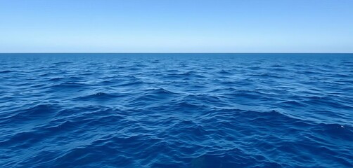 Fototapeta premium Serene deep blue ocean water surface gently rippling under a clear sky, offering a peaceful natural backdrop for design, peaceful, clear