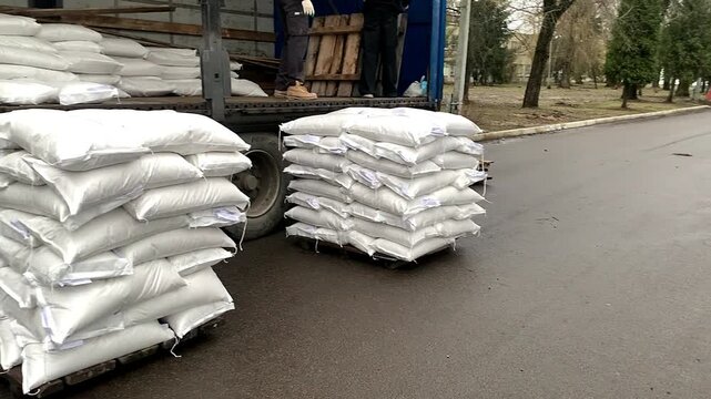 Forklift unloading pallet of sacks from truck.