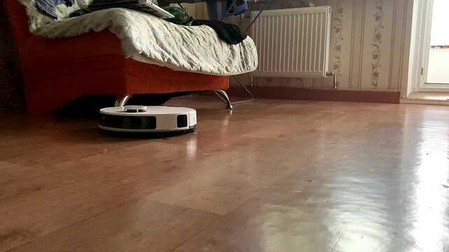 A robot vacuum cleaner cleans the floor in the apartment.