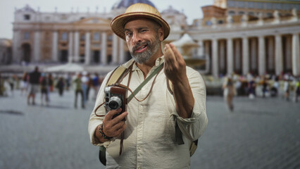 Man with vintage camera and backpack in straw hat points finger to basilica in vatican square;...