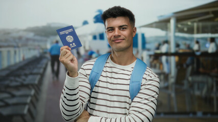 Korean man smiling holding passport on cruise deck outdoors wearing backpack showcasing travel adventure with blue sky and sea in background elevating tourism theme © Krakenimages.com