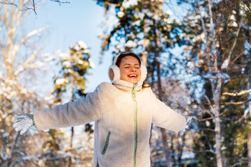 Happy woman wearing warm clothes enjoying winter in forest.