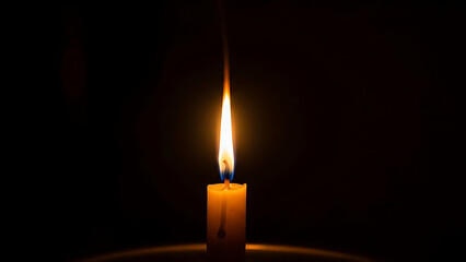 Single yellow wax candle burning in complete darkness creating peaceful warm atmosphere and soft vertical light.