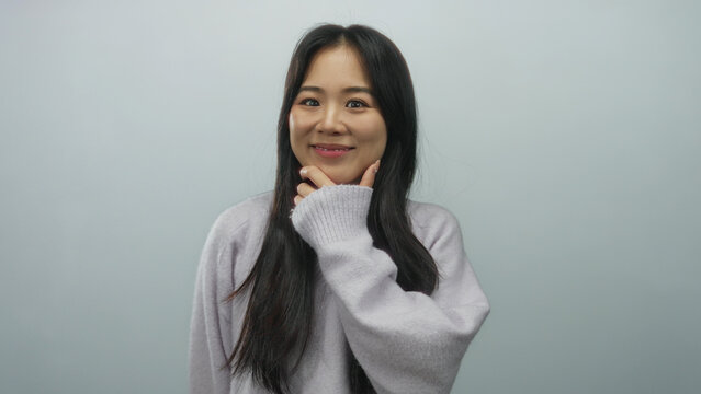 Chinese woman pondering against isolated white background, wearing casual sweater, expressing contemplation, indoors, young female looking thoughtful, serene expression.