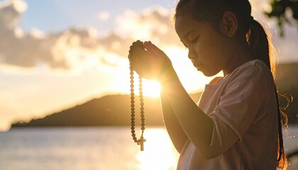 Child Holding Rosary at Sunset by the Water