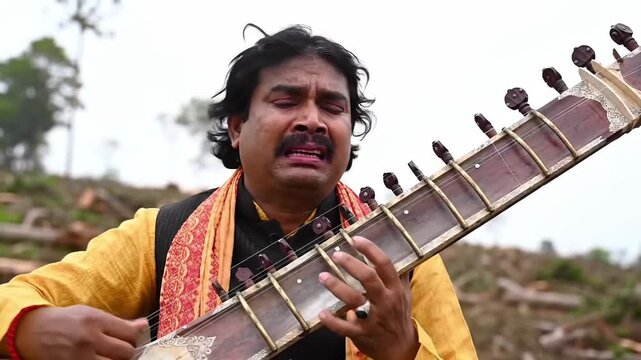 Man playing sitar outside. Musician playing traditional Indian music in nature.