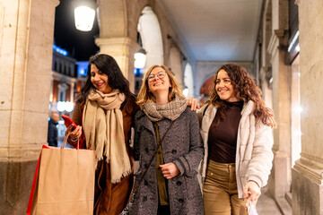 Fototapeta premium Happy women friends enjoying winter city shopping