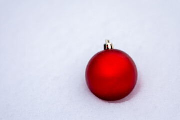 Red Christmas ball ornament on fresh snow with clean white background and copy space. Minimal winter holiday decoration ideal for Christmas design, seasonal advertising and festive branding.