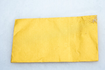Shiny gold envelope, slightly wrinkled, lying on snow. Minimal winter background with copy space, suitable for messages, invitations, marketing and design.