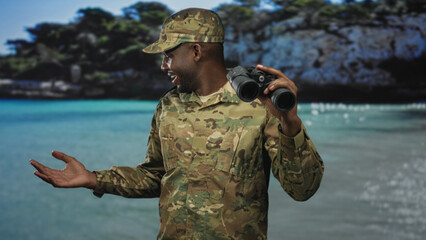 Soldier man in camouflage uniform holding binoculars, open right hand gesture toward sea backdrop...