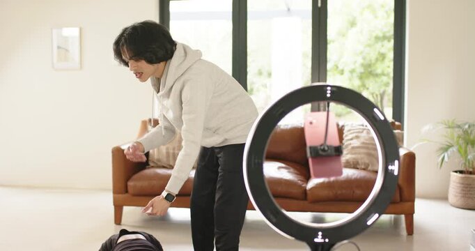 Instructor rummaging bag guiding student stretching on mat by ring light in living room, copy space
