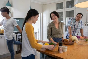 Diverse family preparing vegetables on kitchen island with steel bowl and pasta jars