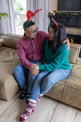 Naklejka premium Mature woman and senior asian man sitting on sofa in living room in antlers by mantel