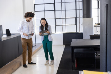 Diverse coworkers discussing reports on tablets in modern open-plan office © wavebreak3