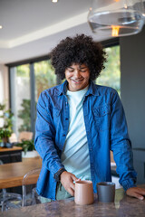 African American man wearing smartwatch reaching for ceramic mug on marble countertop in kitchen © wavebreak3