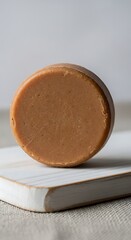 Brown soap bar on white marble slab with beige background