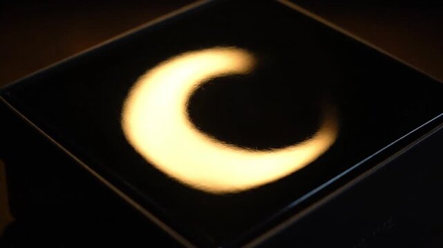 Close-up shot of a solar eclipse projection on a dark surface with a thin white border
