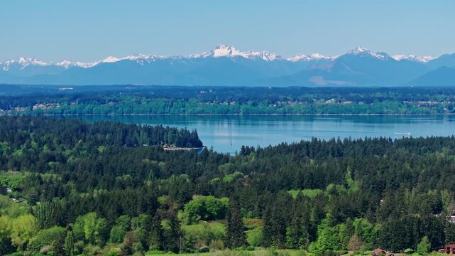 Aerial drone view of Olympic National Park, Seattle, Washington, showcasing a pristine mountain lake surrounded by forest and alpine peaks. Serene, natural landscape.