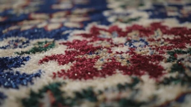 Close-up of a colorful woven rug with red, blue, and green patterns on a white background.